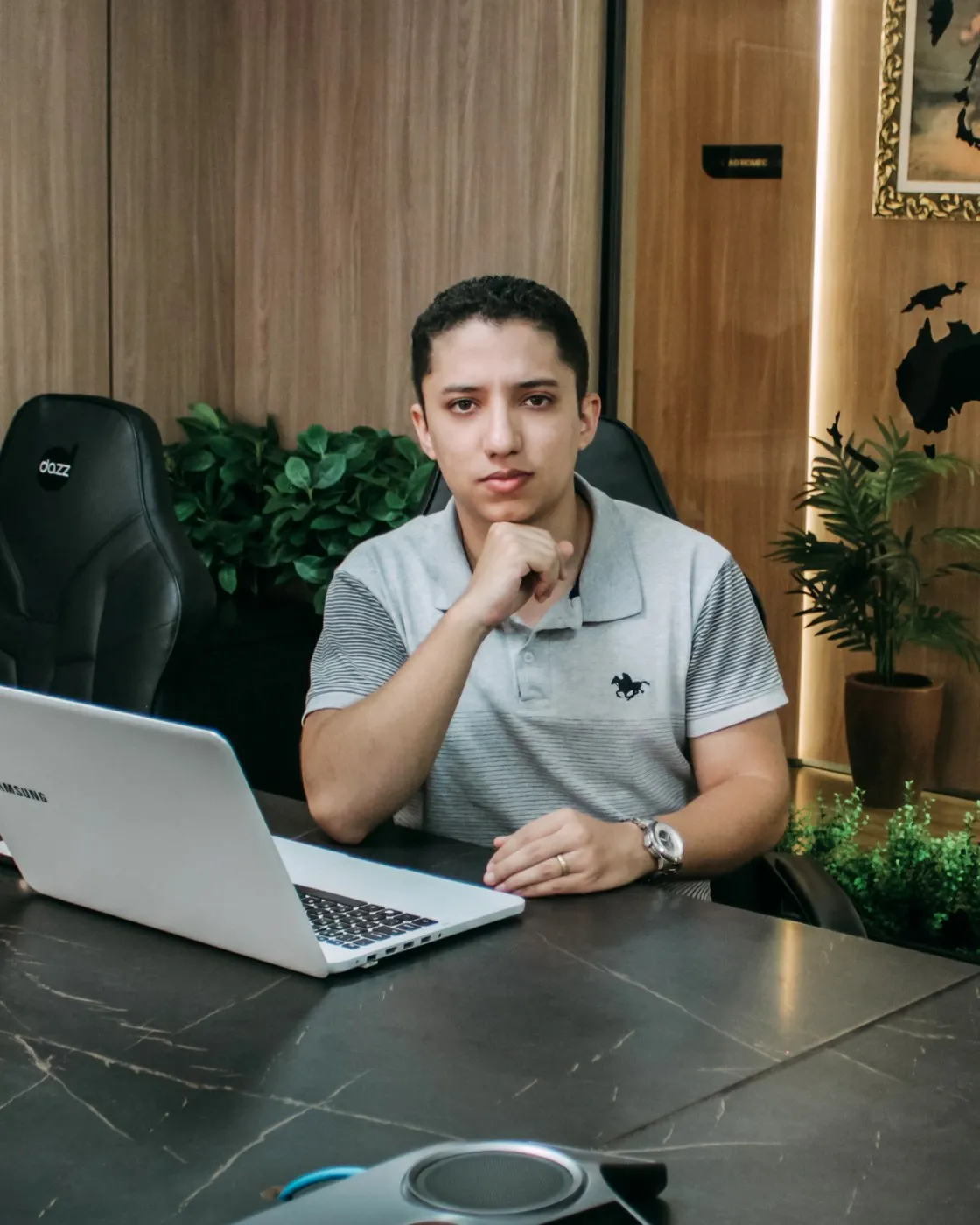 Thiago Carvalho sentado à mesa do escritório com o notebook aberto